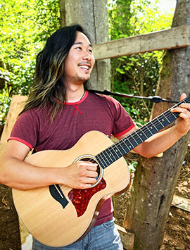 Nate, music therapist, outdoors with guitar
